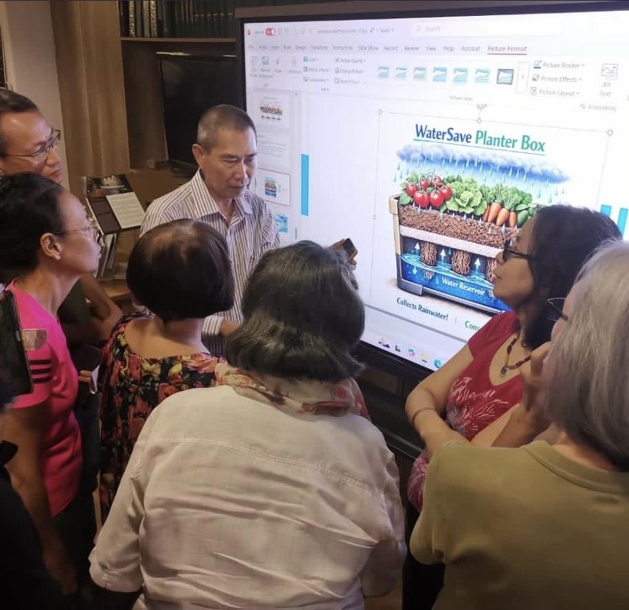 Attendees gathered around a screen reviewing the WaterSave Planter Box design